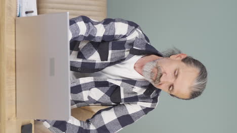 Vertical-video-of-Old-man-looking-at-laptop-is-unmotivated-and-bored.